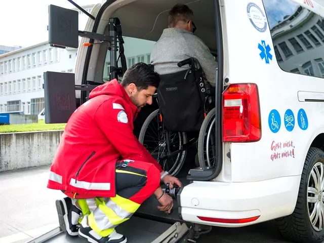 Mobimed-Mitarbeiter kniet am Heck des Fahrzeugs und verankert den Rollstuhl eines Patienten