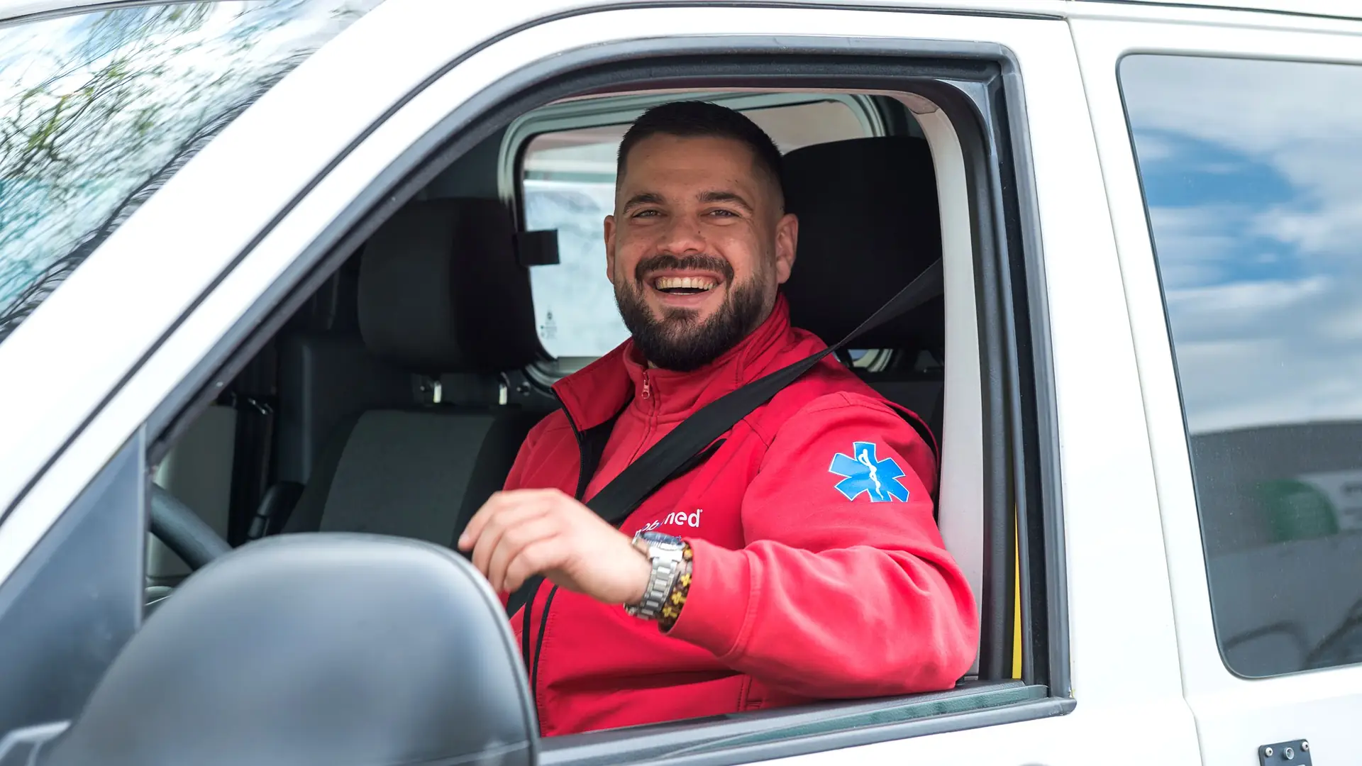 Lachender Fahrer von Mobimed am Steuer eines Patiententransport-Fahrzeugs